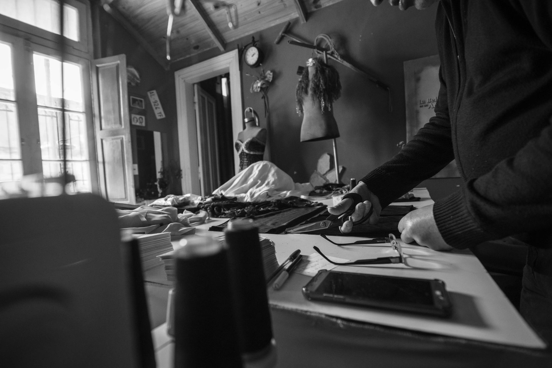 A black and white image capturing a seamstress working in a vintage workshop with tools.