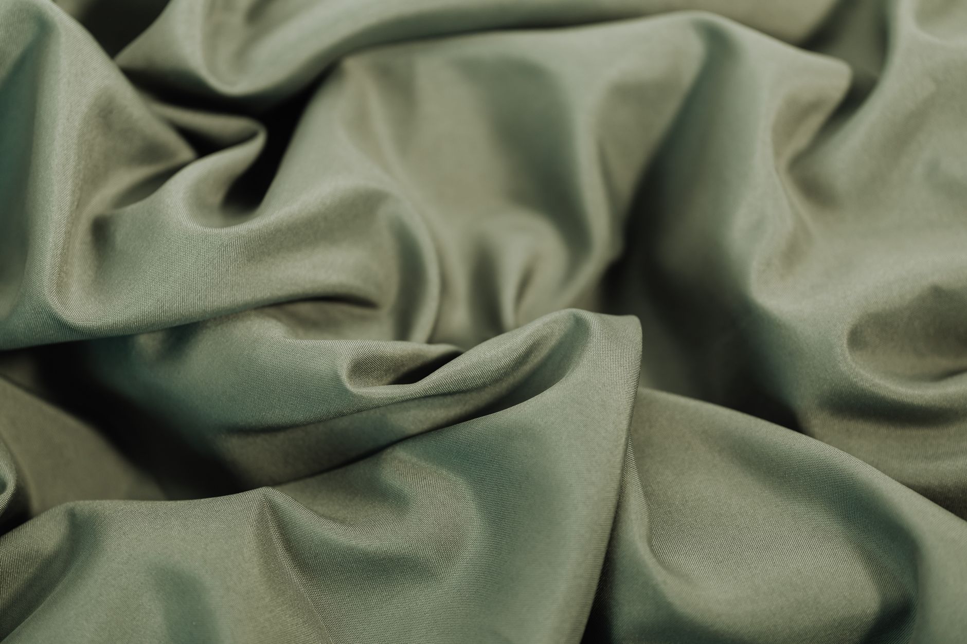 Close-up of a rippled green fabric texture, perfect for backgrounds or wallpaper.