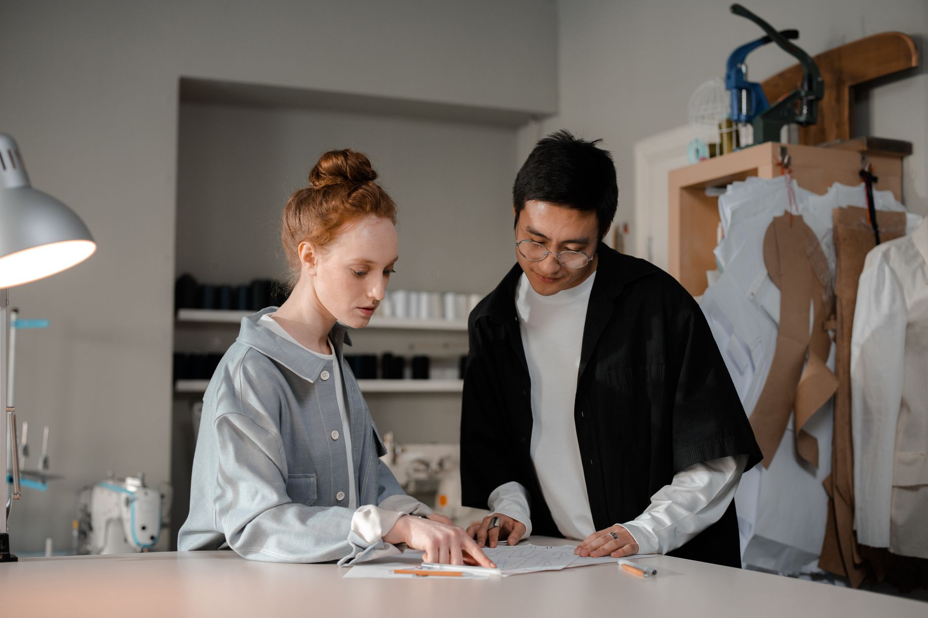 Two designers collaborate in a stylish fashion studio, focusing on their creative work.
